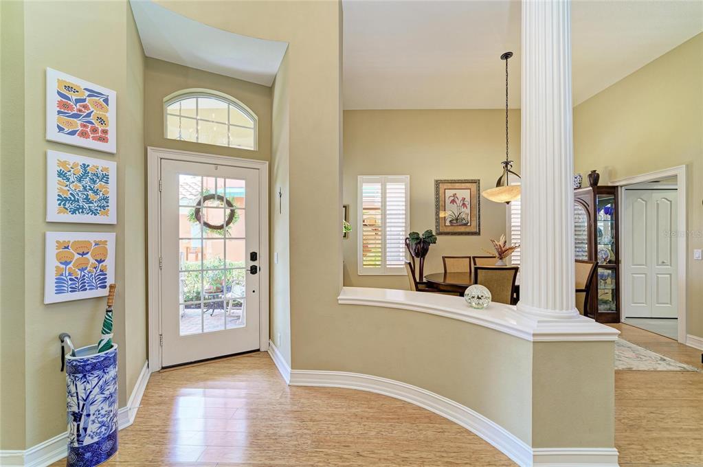 An entryway with light wood flooring, a white front door, and a decorative column — 308 10TH AVENUE E, PALMETTO, FL