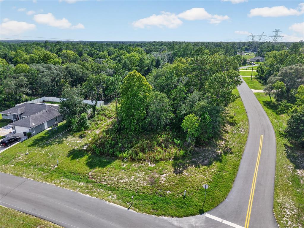 An aerial view shows a vacant, wooded residential lot situated at a curved road intersection — 0000 SW 155TH STREET ROAD, OCALA, FL