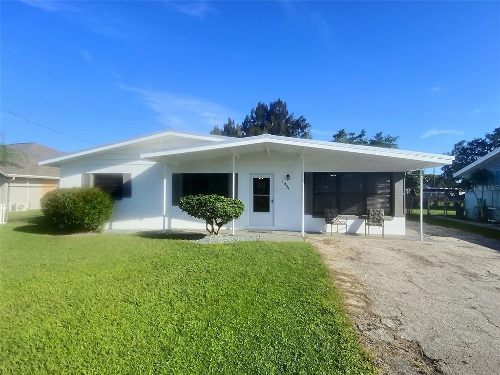 A single-story white house with a covered front porch and a paved driveway — 1334 SUNSET DRIVE, SEBRING, FL