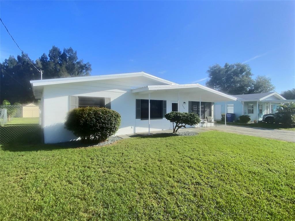 A white single-story house with a covered front porch and a grassy front yard — 1334 SUNSET DRIVE, SEBRING, FL