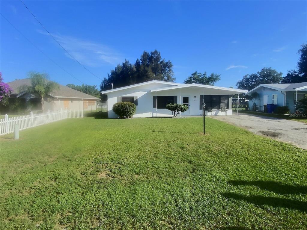 A white single-story house with a front porch, a lawn, and a white picket fence — 1334 SUNSET DRIVE, SEBRING, FL