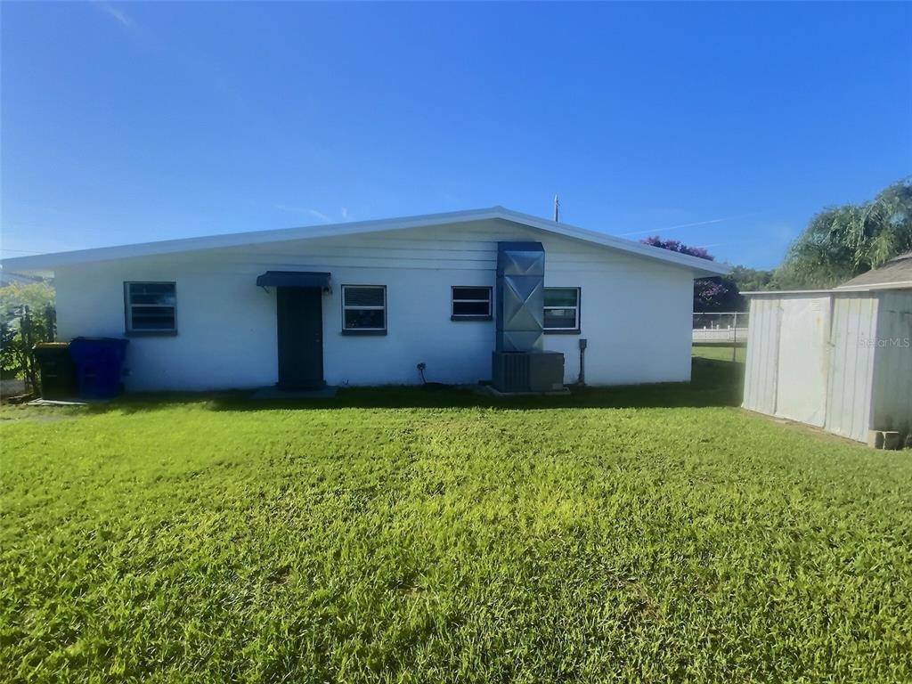 The exterior of a white house features a metal HVAC unit and a storage shed — 1334 SUNSET DRIVE, SEBRING, FL