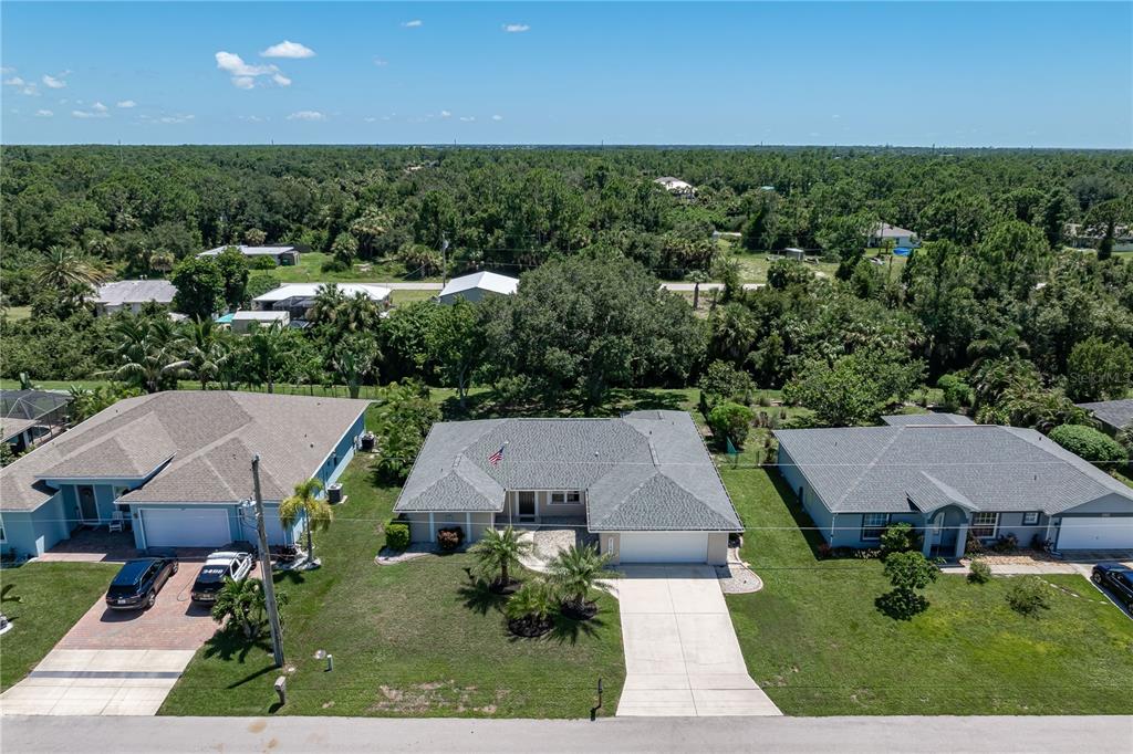An aerial view shows three suburban houses with gray roofs and driveways surrounded by trees — 313 GOLD TREE, PUNTA GORDA, FL