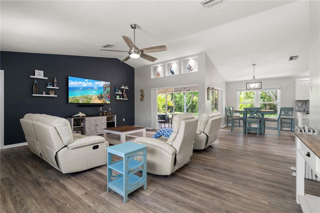 A living room with a dark accent wall, white leather recliners, and an adjacent dining area — 313 GOLD TREE, PUNTA GORDA, FL