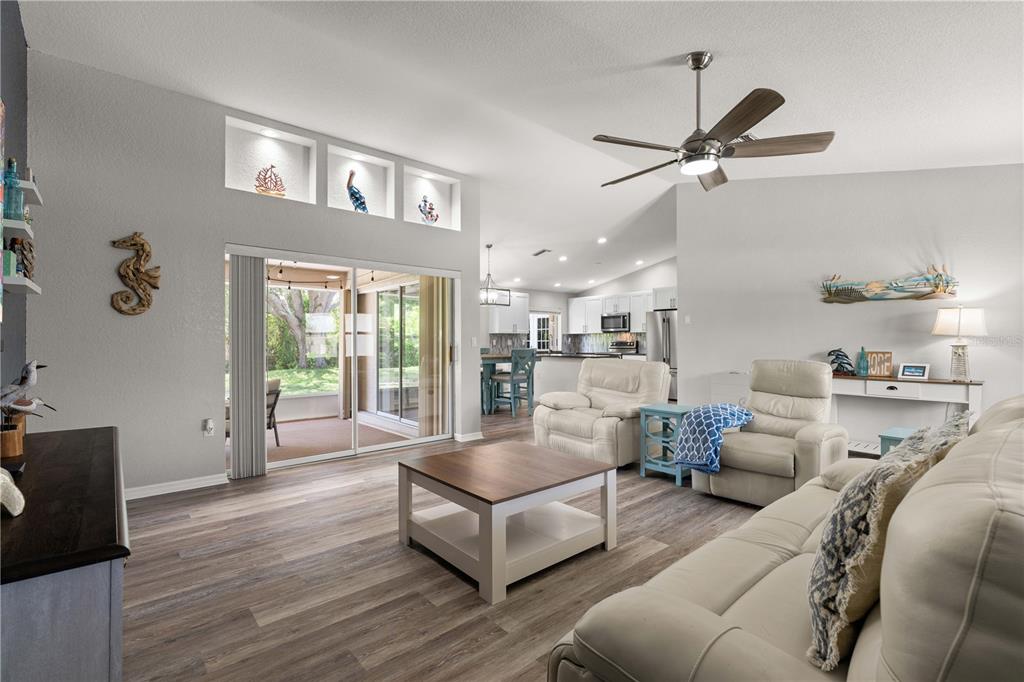 A living room with light wood floors, a ceiling fan, and sliding doors to a patio — 313 GOLD TREE, PUNTA GORDA, FL