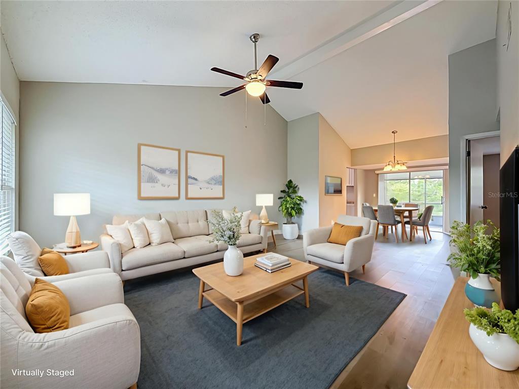 A living room with vaulted ceilings, a ceiling fan, and neutral furniture on a rug — 7606 WOODLAND OAKS COURT, TAMPA, FL