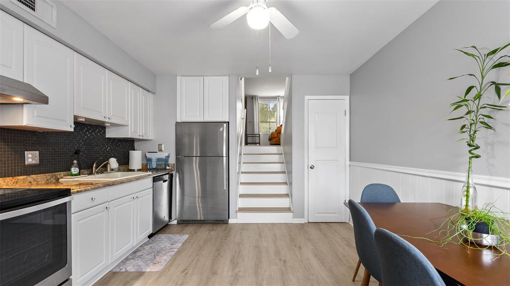 A kitchen features white cabinets, stainless steel appliances, granite countertops, and stairs leading upward — 4227 LA PALMA COURT, TAMPA, FL