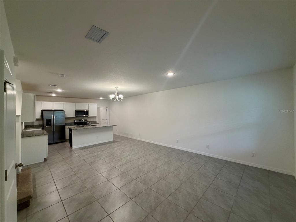 An open-concept kitchen and dining area features tile flooring, white cabinetry, and granite countertops — 614 CHEVAL LANE, DEBARY, FL