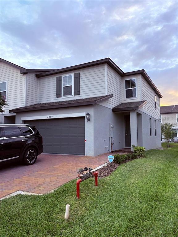 A two-story house with a gray garage, light siding, and a brick paver driveway — 2040 MILKWEED STREET, OCOEE, FL