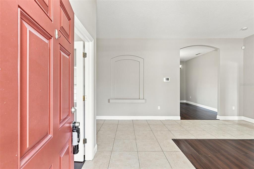 An entryway with a red door, light tile flooring, and an arched wall niche — 1955 LINDHURST AVENUE, DELTONA, FL
