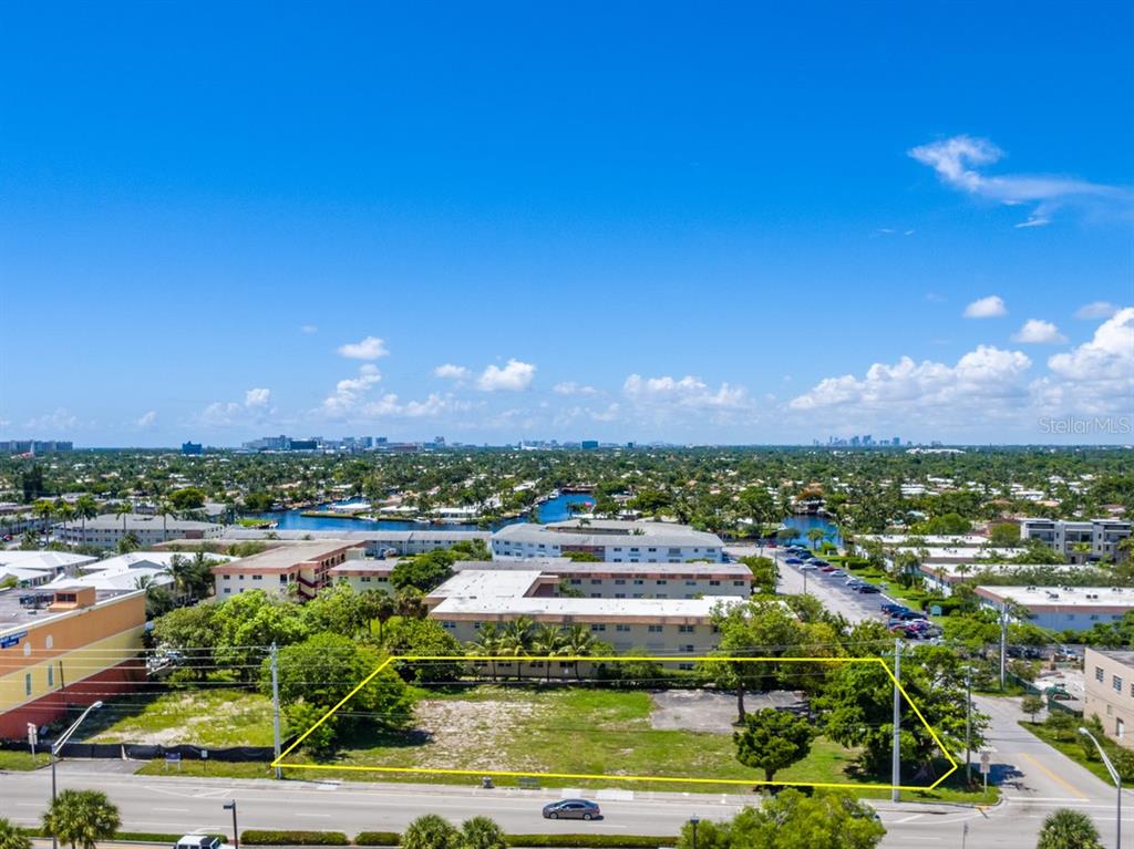 An aerial view shows a rectangular vacant lot bordered by a road and trees — 600 E ATLANTIC BOULEVARD, POMPANO BEACH, FL