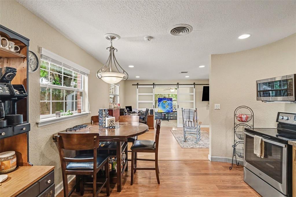 A kitchen and dining area with wood floors, a round table, and sliding barn doors — 2625 GARDEN STREET, TITUSVILLE, FL