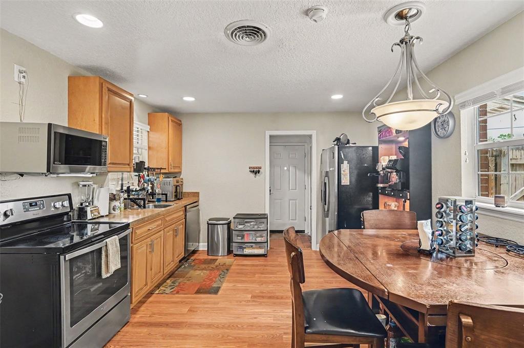 A kitchen features wood cabinets, stainless steel appliances, a dining table, and wood-look flooring — 2625 GARDEN STREET, TITUSVILLE, FL