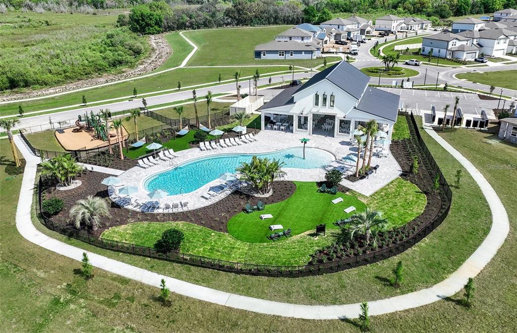 An aerial view of a community clubhouse featuring a swimming pool, playground, and surrounding landscaping — 465 WATERFORD DRIVE, LAKE ALFRED, FL