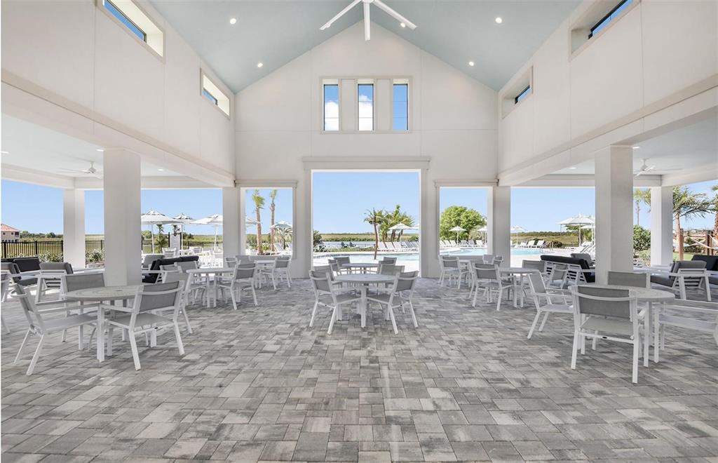 An open-air pavilion features a vaulted ceiling, stone paver flooring, and views of a pool — 465 WATERFORD DRIVE, LAKE ALFRED, FL