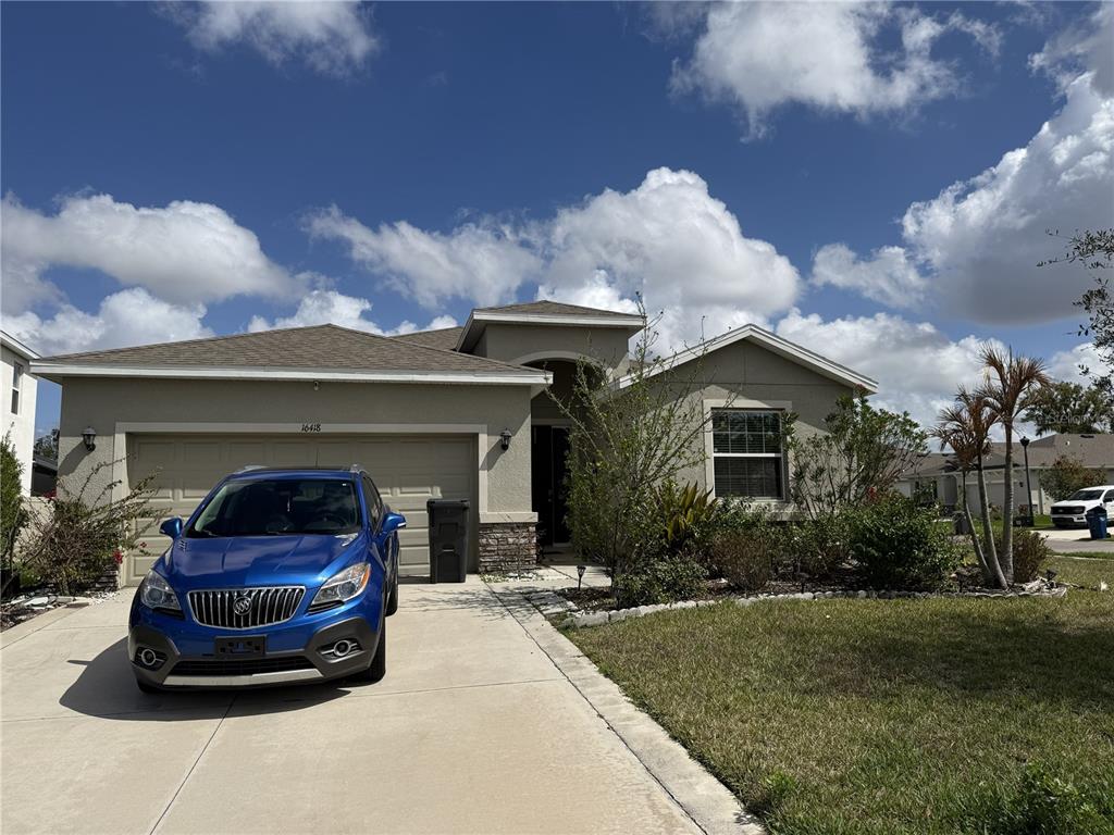 A tan single-story house with a two-car garage and a blue car in the driveway — 16418 WOODSIDE GLEN, PARRISH, FL