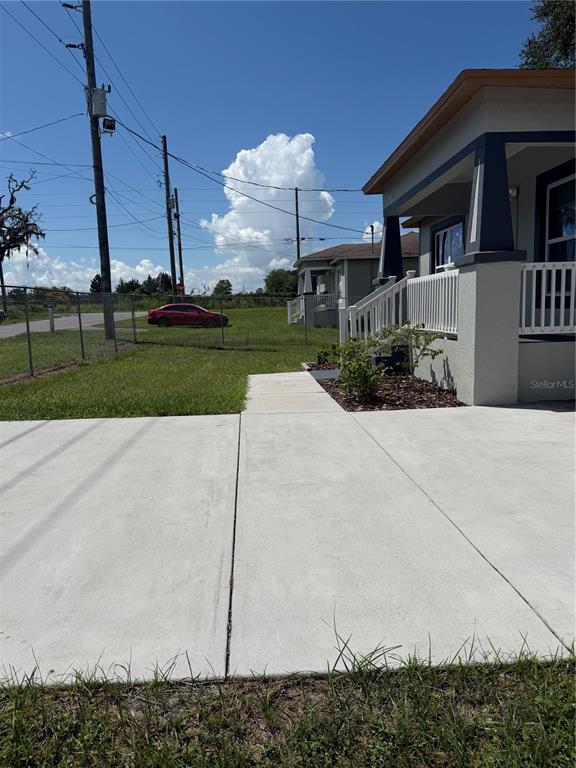 A concrete driveway leads to the front porch of a house with a fenced yard — 21015 MARKET STREET, DADE CITY, FL