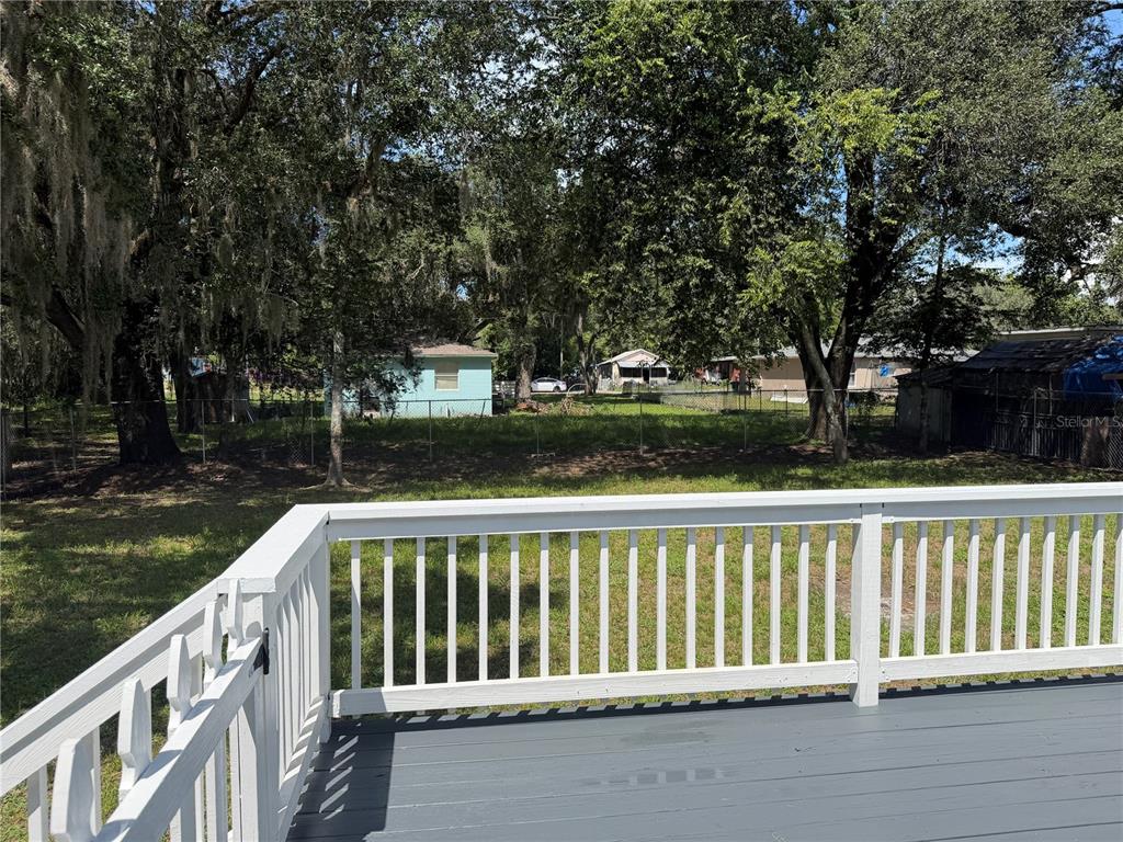 A view from a gray wooden deck with white railings looking out toward a backyard — 21015 MARKET STREET, DADE CITY, FL