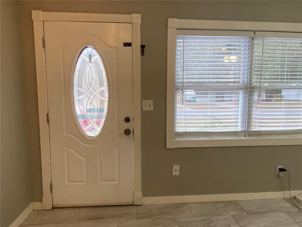 An interior view shows a white front door with a decorative glass insert and tile flooring — 39656 MEADOWOOD LOOP, ZEPHYRHILLS, FL