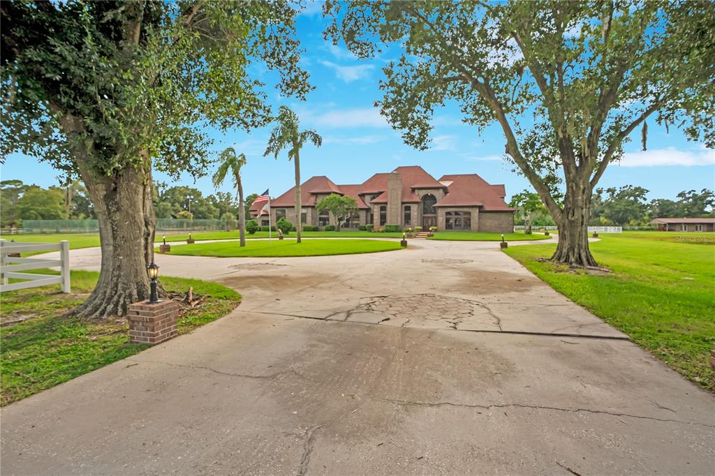 A large brick house with a red roof sits at the end of a long driveway — 4410 ALBRITTON ROAD, ST CLOUD, FL