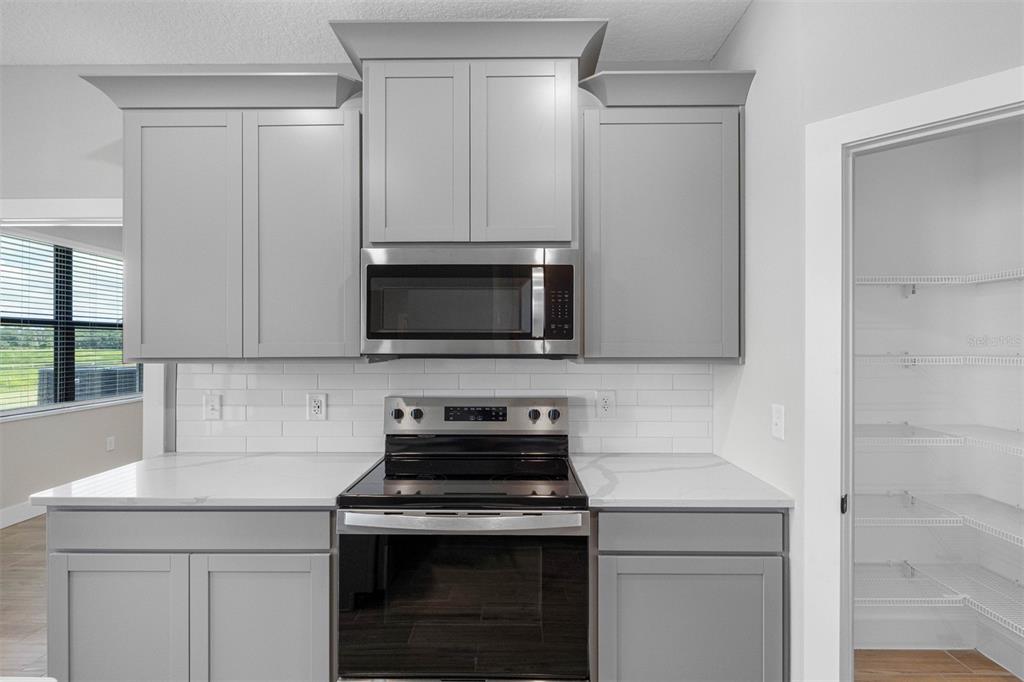 A kitchen features gray cabinets, stainless steel appliances, white countertops, and a white subway tile backsplash — 13501 WALDEN SHEFFIELD ROAD, DOVER, FL