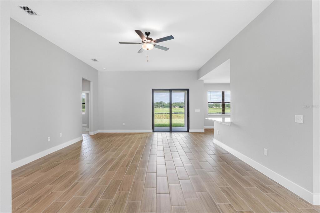 An open-concept living area features light gray walls, wood-look tile flooring, and sliding glass doors — 13501 WALDEN SHEFFIELD ROAD, DOVER, FL