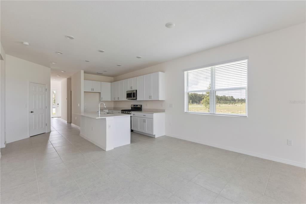 A bright kitchen features white cabinets, a central island, and tile flooring — 9128 WILDLIGHT TRAIL, WILDWOOD, FL