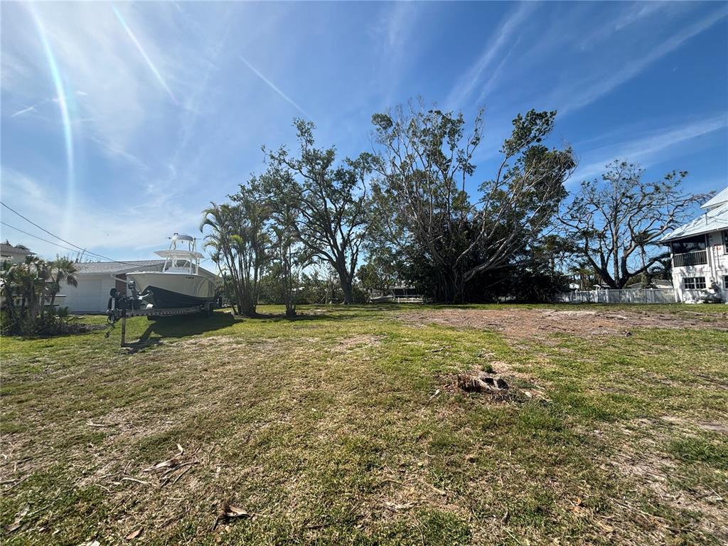 A grassy vacant lot features a boat on a trailer and several large mature trees — 4417 DOLPHIN LANE, PALMETTO, FL