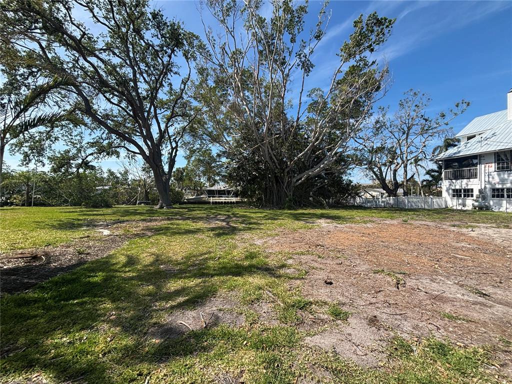 A large, grassy vacant lot features mature trees and a view of a nearby canal — 4417 DOLPHIN LANE, PALMETTO, FL