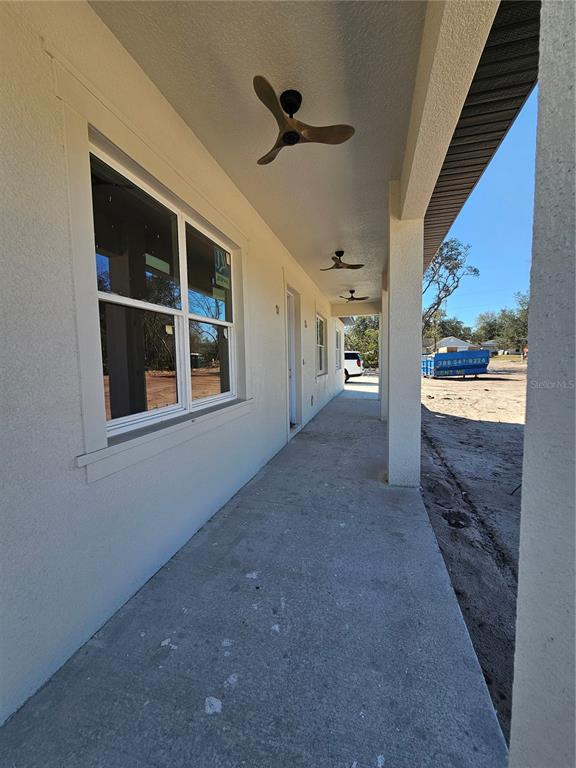 A concrete porch with three ceiling fans runs along the side of a stucco house — 2410 LAKE TINY ROAD, DELTONA, FL