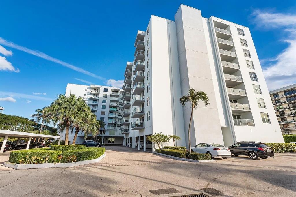 A multi-story white apartment building with balconies and a paved parking area in front — 3450 S OCEAN BOULEVARD UNIT 615, PALM BEACH, FL
