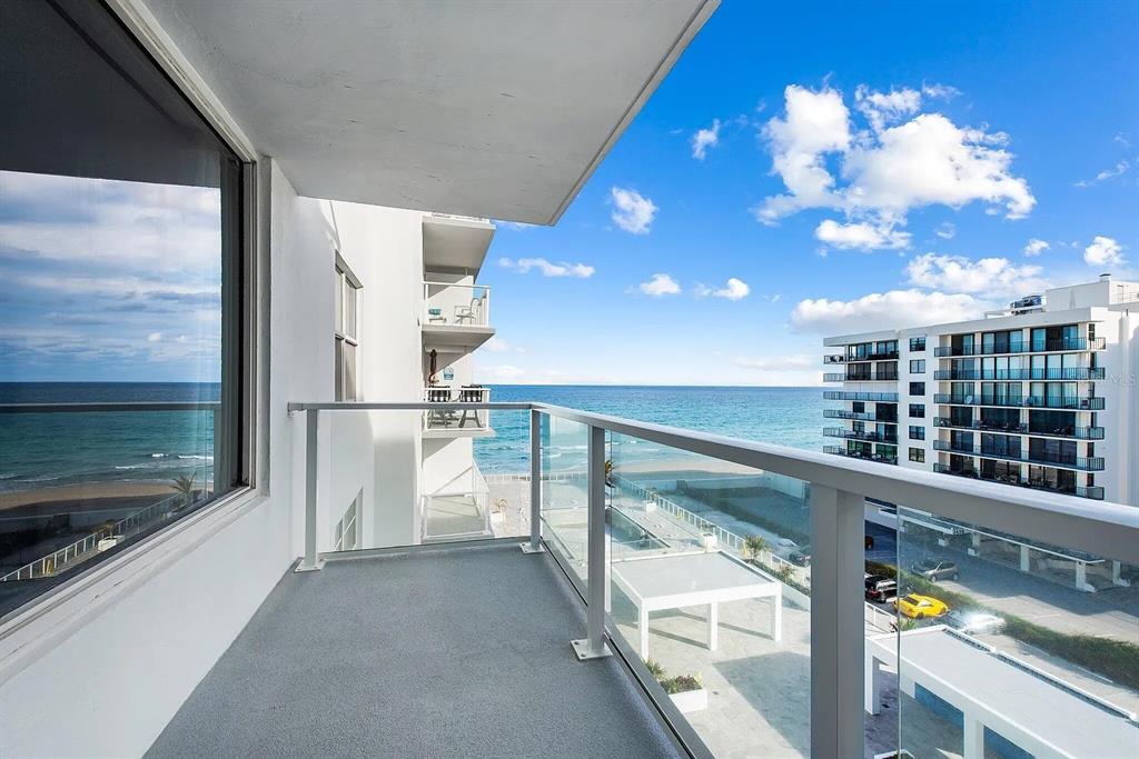 A balcony with a glass railing overlooks the ocean and a neighboring apartment building — 3450 S OCEAN BOULEVARD UNIT 615, PALM BEACH, FL
