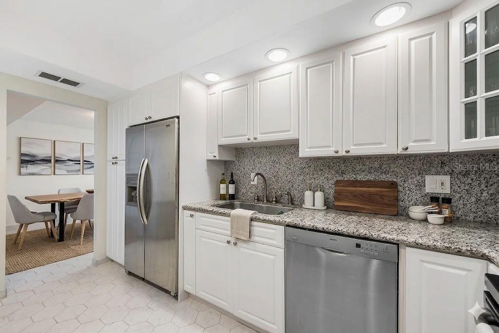 A kitchen with white cabinets, granite countertops, stainless steel appliances, and a tile floor — 3450 S OCEAN BOULEVARD UNIT 615, PALM BEACH, FL