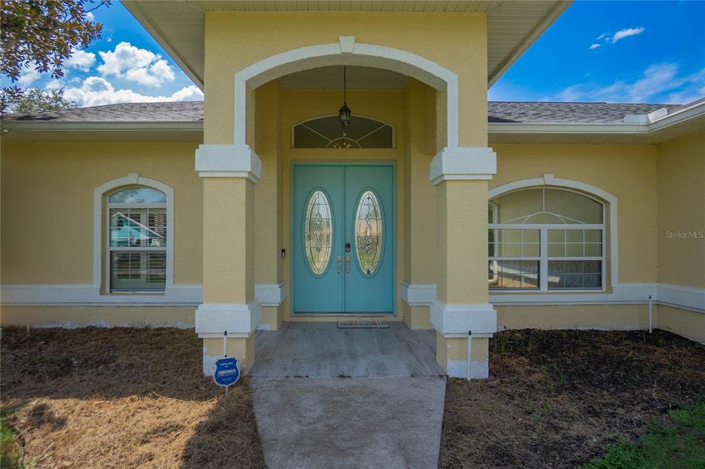The exterior of a yellow house features a light blue double front door and columns — 3200 S FRANKLIN TERRACE, INVERNESS, FL