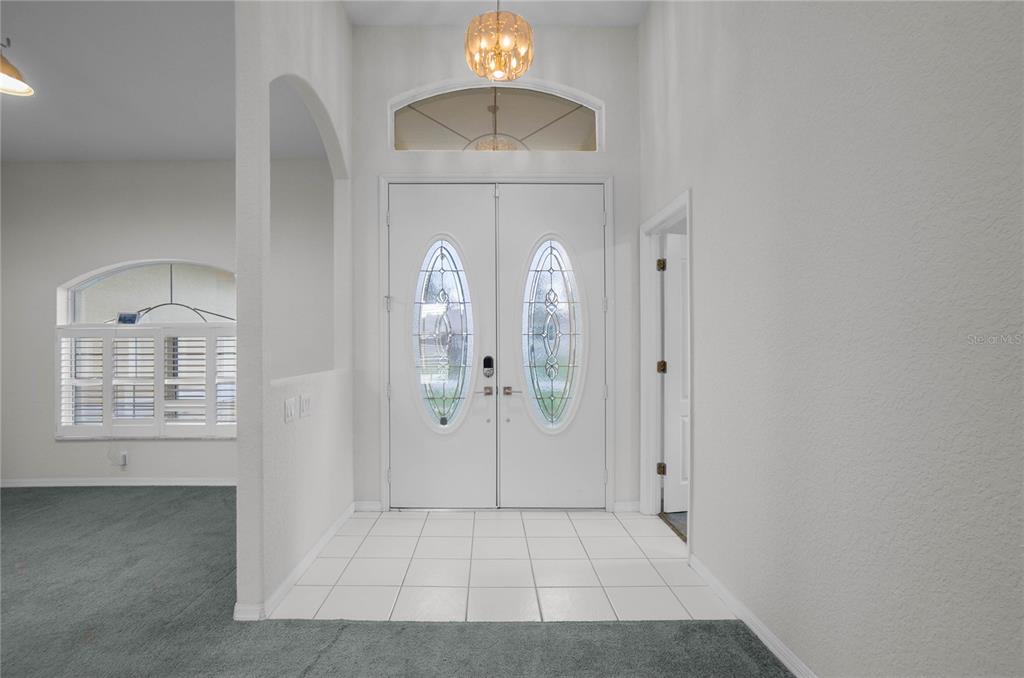 An entryway features a double front door with glass inserts, tile flooring, and a chandelier — 3200 S FRANKLIN TERRACE, INVERNESS, FL