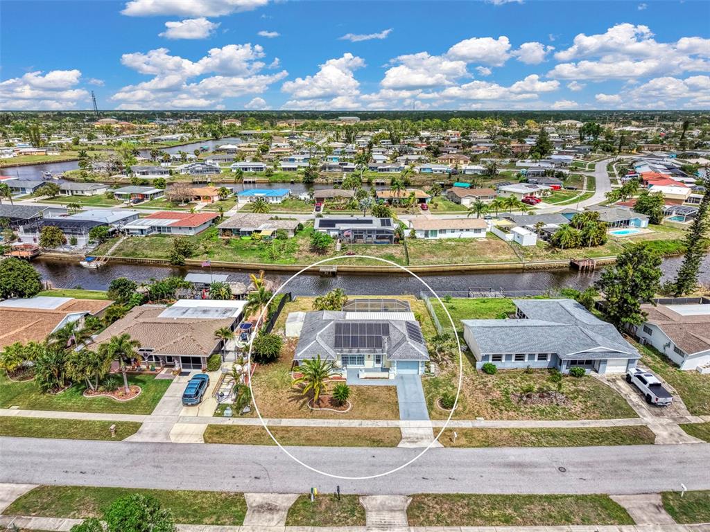 An aerial view shows a single-story house with solar panels and a pool cage — 6282 FABIAN ROAD, NORTH PORT, FL