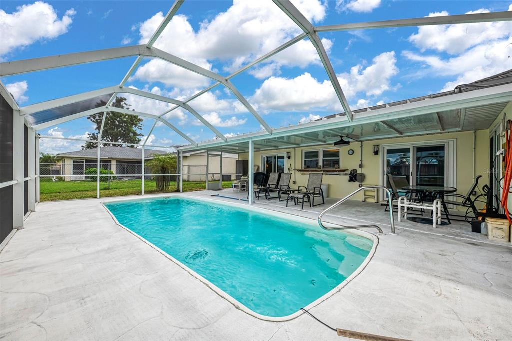 A screened-in swimming pool area with a concrete deck and patio furniture — 6282 FABIAN ROAD, NORTH PORT, FL