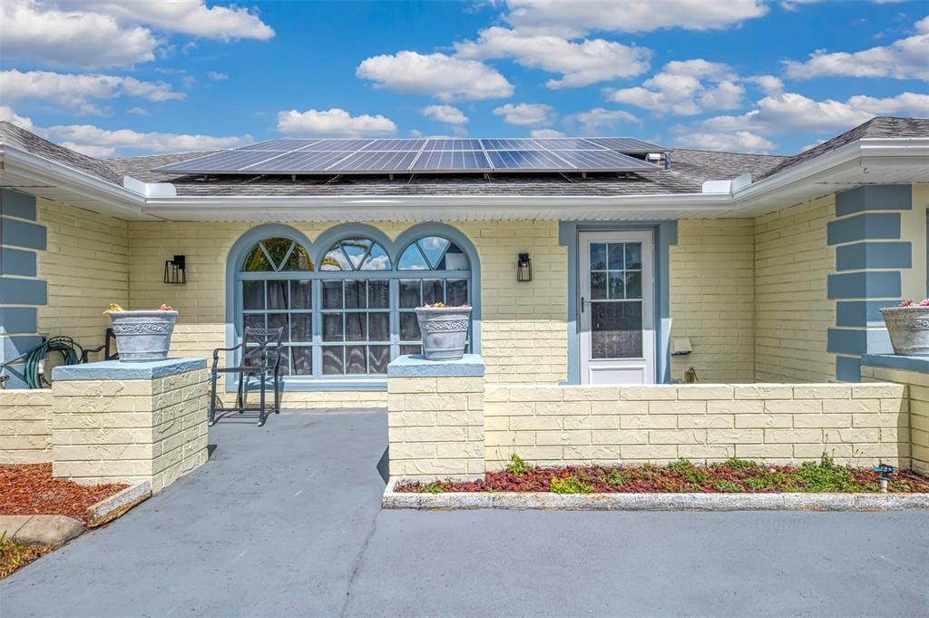 A yellow brick house exterior features a front patio, arched windows, and rooftop solar panels — 6282 FABIAN ROAD, NORTH PORT, FL
