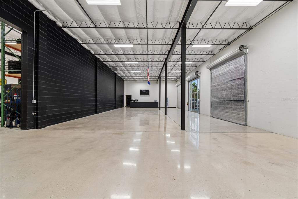 A spacious industrial warehouse interior features polished concrete floors, black accent walls, and exposed ceilings — 15552 US 301, DADE CITY, FL