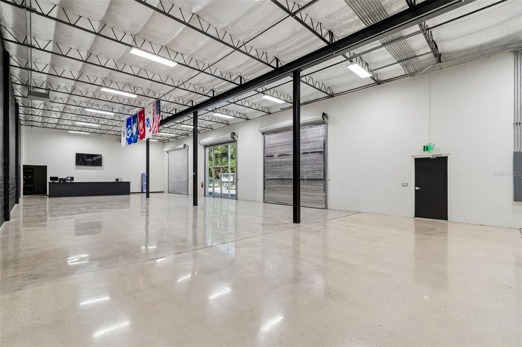 A large, open warehouse space features polished concrete floors, white walls, and exposed ceiling trusses — 15552 US 301, DADE CITY, FL