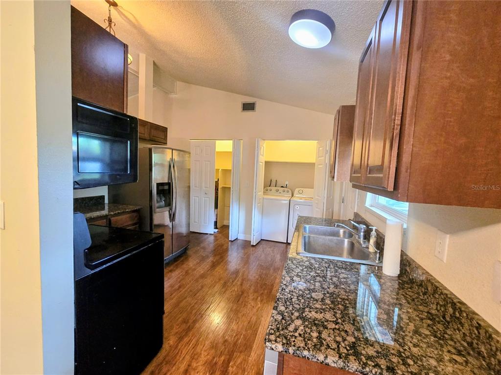 A living room with wood-look flooring, a stone fireplace, a ceiling fan, and a front door — 13581 SE 48TH COURT, SUMMERFIELD, FL