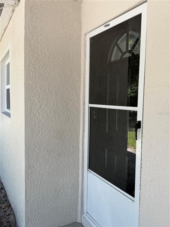 A white storm door with a screen panel is installed on a beige stucco exterior wall — 783 ELDRIDGE STREET, ORLANDO, FL