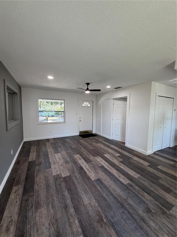 A living room with wood-look flooring, white walls, a ceiling fan, and a front door — 783 ELDRIDGE STREET, ORLANDO, FL