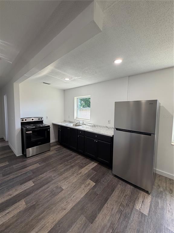 A kitchen features dark cabinets, a stainless steel stove, a refrigerator, and wood-look flooring — 783 ELDRIDGE STREET, ORLANDO, FL