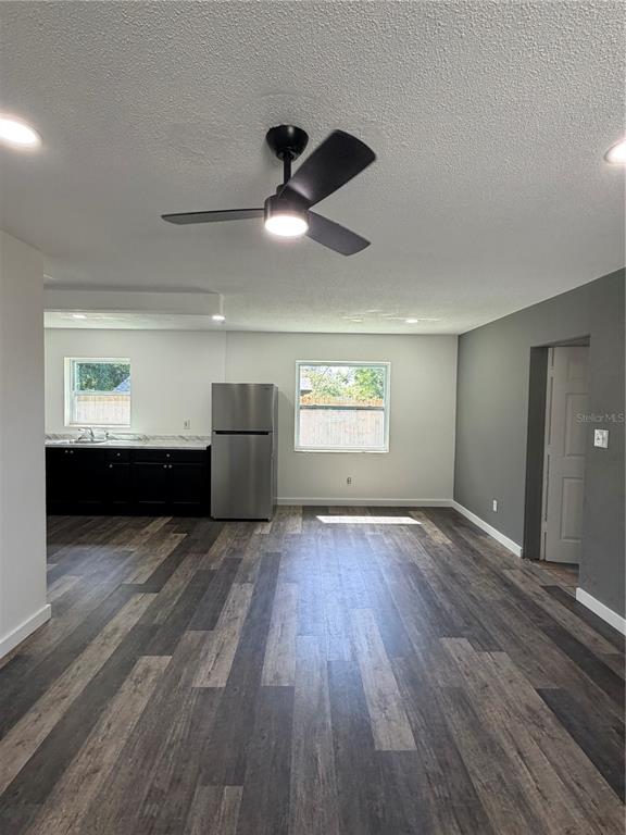 An open-concept kitchen and living area features dark wood-look flooring, black cabinets, and a ceiling fan — 783 ELDRIDGE STREET, ORLANDO, FL