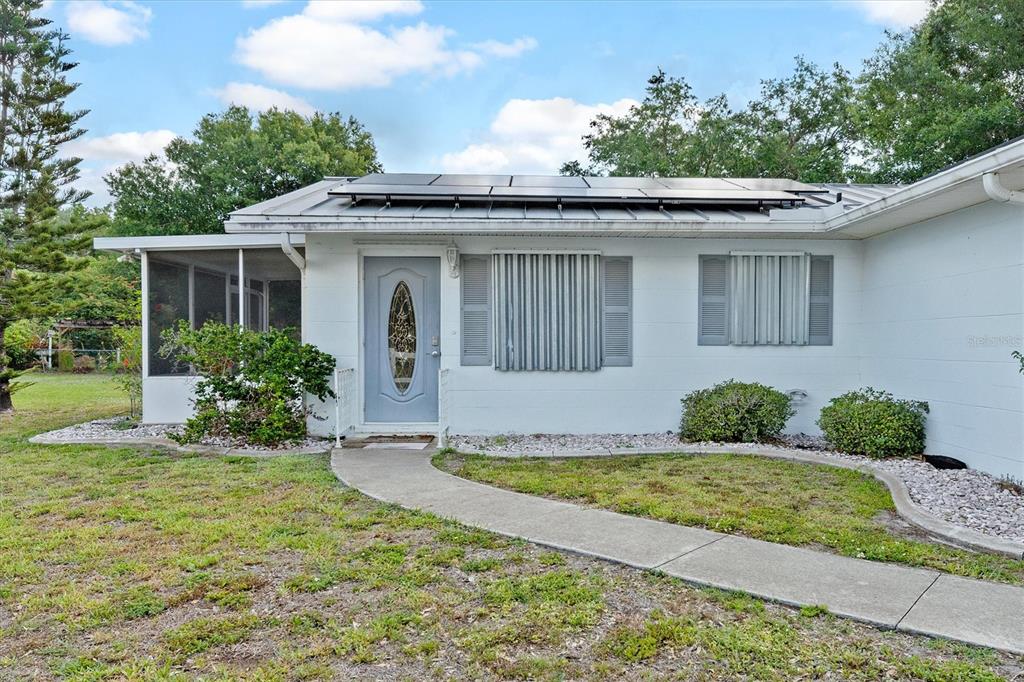 A white single-story house with a metal roof, solar panels, and a front walkway — 8126 RIVERSIDE DRIVE, PUNTA GORDA, FL