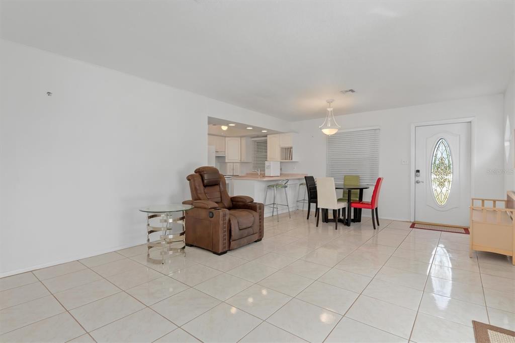 A living and dining area with white walls, light tile flooring, and a brown recliner — 8126 RIVERSIDE DRIVE, PUNTA GORDA, FL