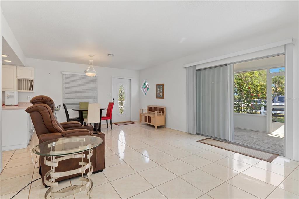 A living and dining area with light tile floors, a brown recliner, and sliding glass doors — 8126 RIVERSIDE DRIVE, PUNTA GORDA, FL