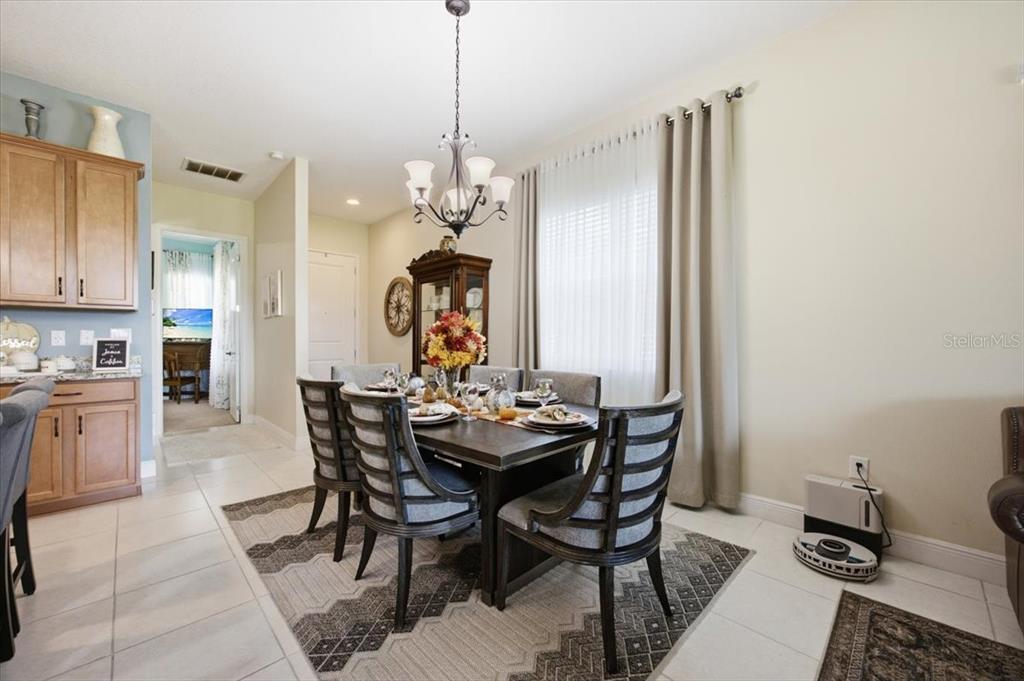 A dining room features a dark wood table with six chairs, a chandelier, and tile flooring — 2541 YELLOW BRICK ROAD, ST CLOUD, FL