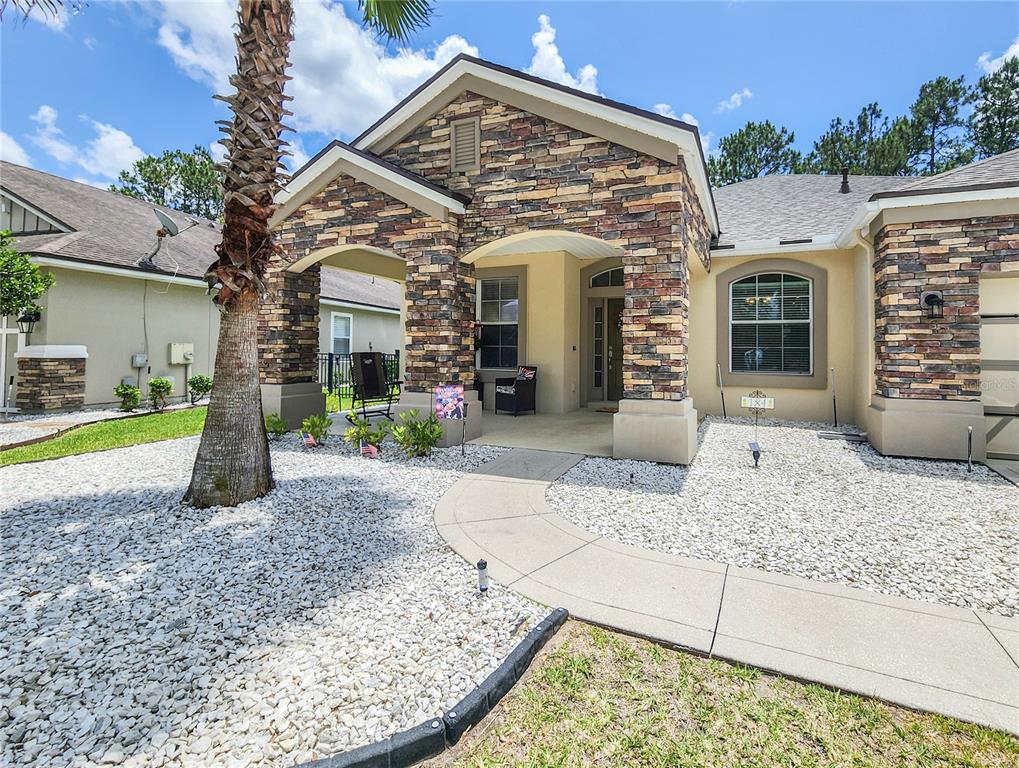 A single-story house with a stone facade, a covered entryway, and a white rock front yard — 184 S ARABELLA WAY, ST JOHNS, FL